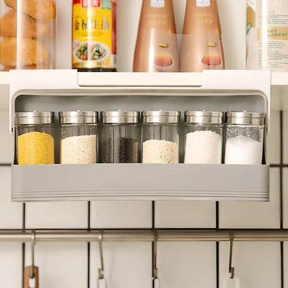 Gray kitchen storage rack with six seasoning bottles mounted on wall using punch-free adhesive system
