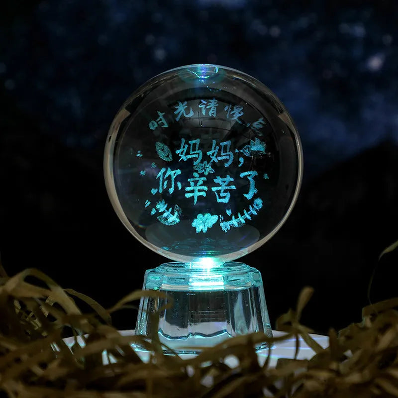 Transparent crystal ball ornament with inner carving of clouds, shown on a wooden table.