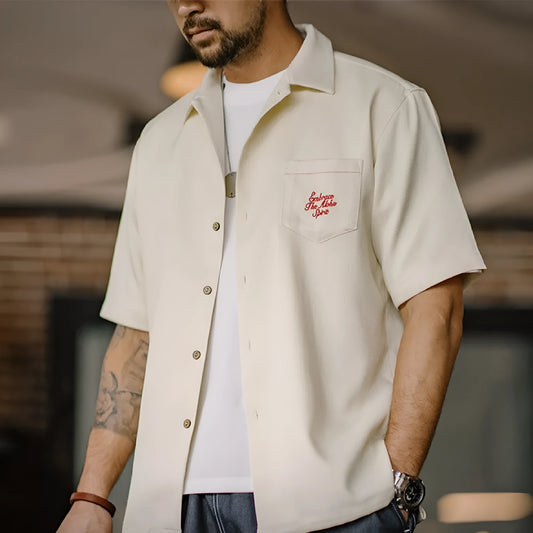 Light apricot men's shirt with a bamboo plant pattern and a Cuban collar laid flat.