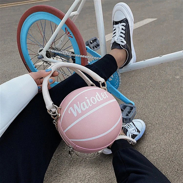 Basketball-shaped handbag with adjustable shoulder strap in pink, white, black, and brown