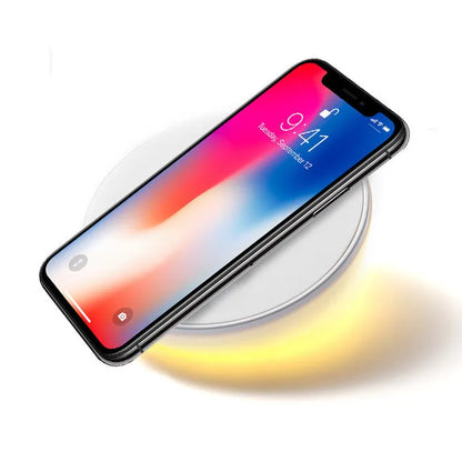 White 10W QI wireless charging pad with digital clock display and night light on a wooden surface.