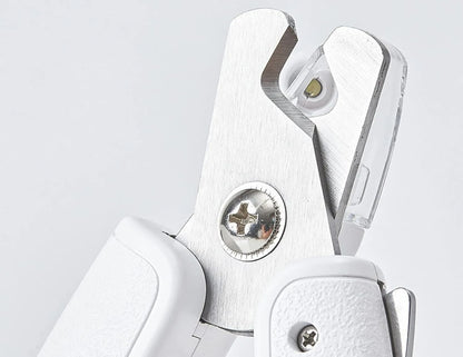 White pet nail clippers with LED light, anti-splash guard, and built-in nail file on a flat surface.