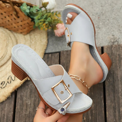 Women's black chunky heel slippers with a metal buckle on the strap and a rubber sole.