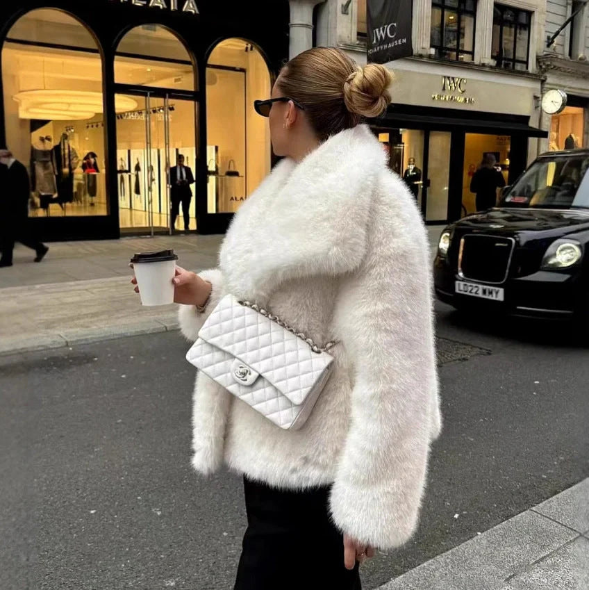 Women's white artificial fur coat with large lapel, long sleeves, and deep pockets shown in street fashion setting