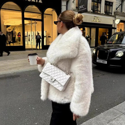 Women's white artificial fur coat with large lapel, long sleeves, and deep pockets shown in street fashion setting