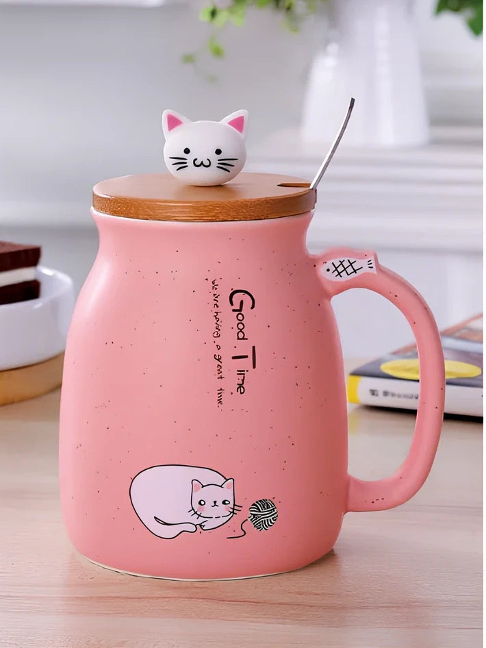 Pink ceramic mug with cartoon cat design, wooden lid, and stainless steel spoon on table