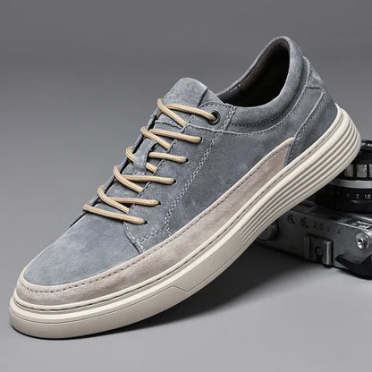 Men's grey low-top casual leather skate shoes with round toe and flat rubber sole on a wooden surface.