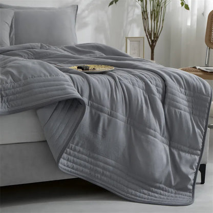 Lightweight plain coloured polyester summer quilt on a bed