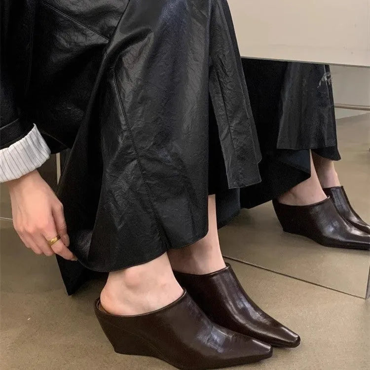 Women's black wind wedge closed toe half slippers on a plain background.