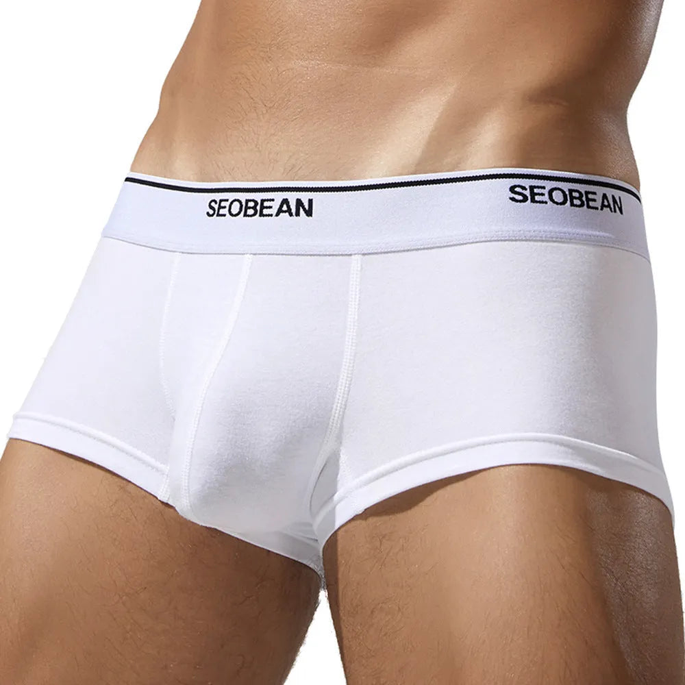 Men's solid colour cotton low waist boxers in white, blue grey, cyan, and black on a size label.