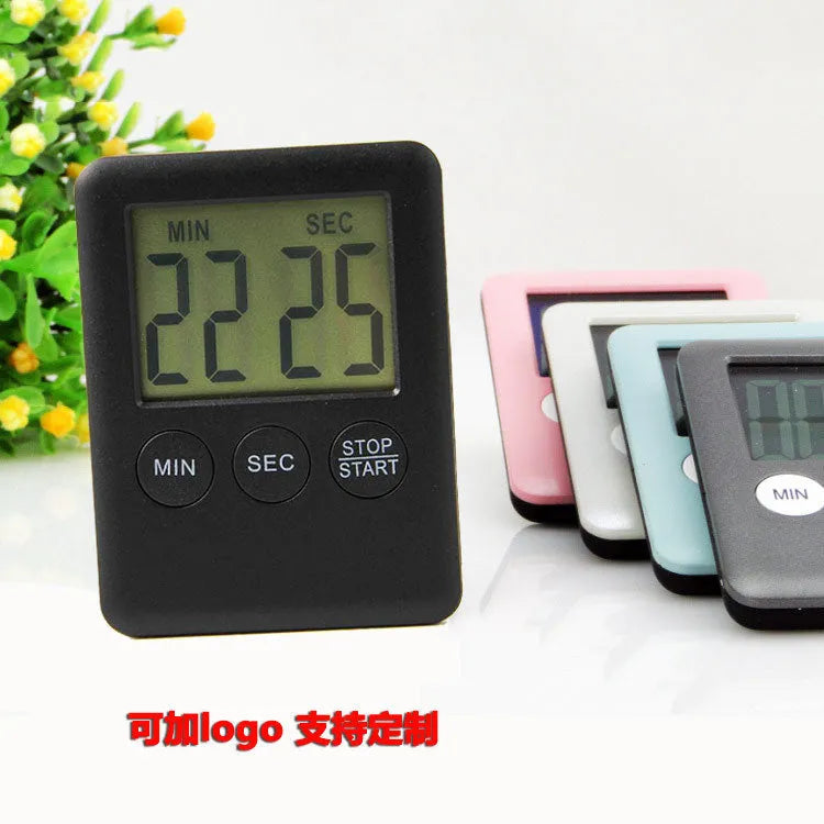 Black and white metal kitchen timer with magnetic back on a refrigerator door