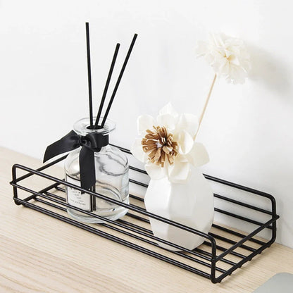 Black wrought iron bathroom shelf, 60cm long with drainage holes, holding shampoo bottles over tub edge