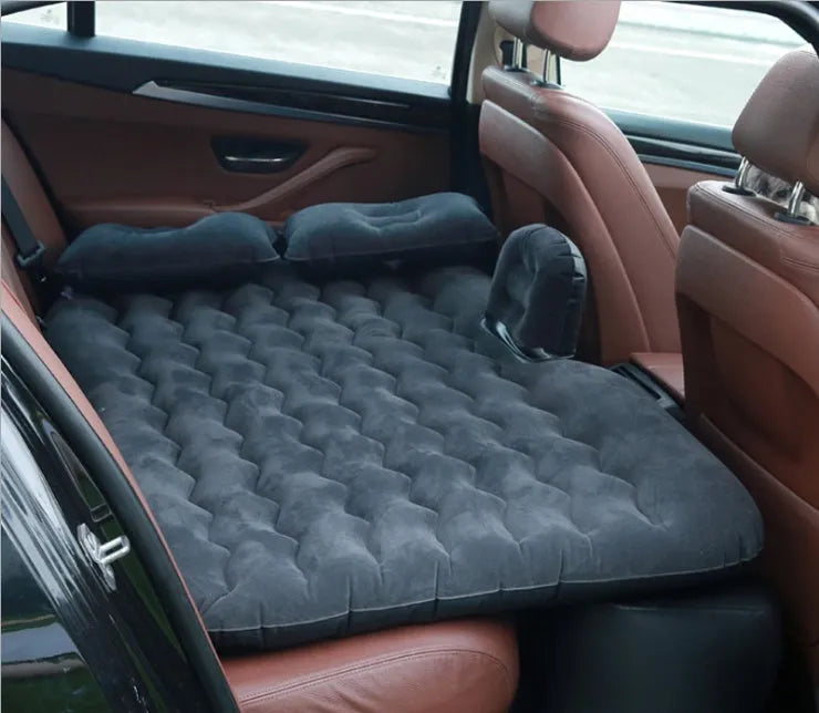 Black inflatable car bed with flocked surface and two pillows, shown folded into a chair inside a vehicle.