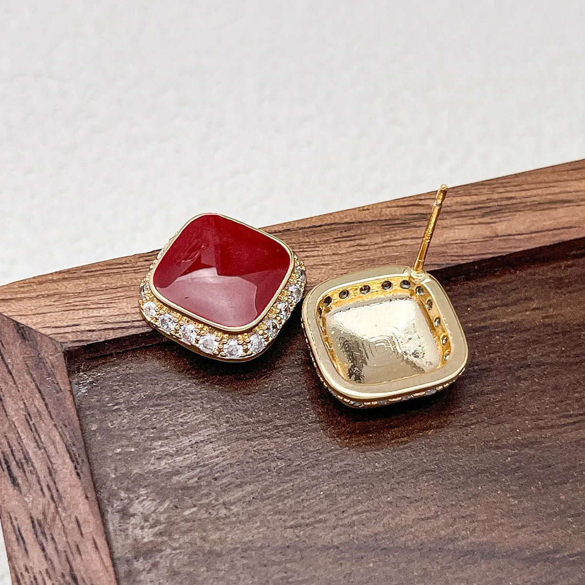Red square alloy earrings with an inlaid geometric design, shown from the front.