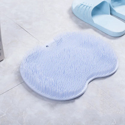 Orange non-slip massage bath brush with silicone bristles and suction cup base on shower floor