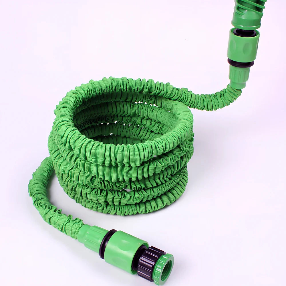 Expandable flexible water hose with spray gun showing green colour and extended length with water spraying in cone pattern