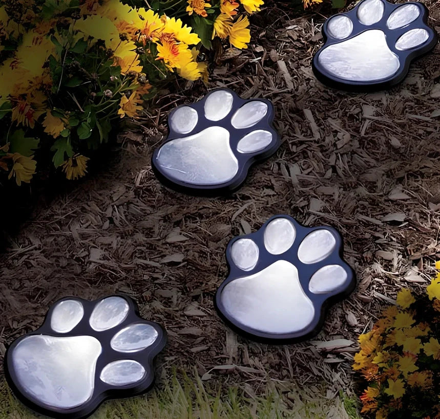 Four black paw-shaped solar garden lights with connecting wire and central solar panel for automatic outdoor illumination
