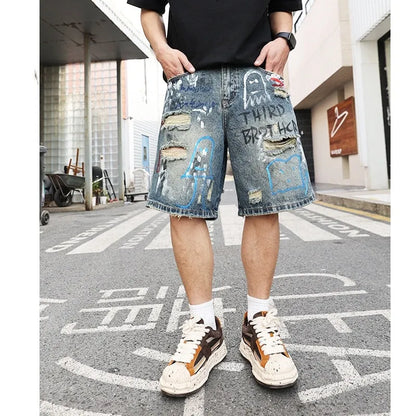 Blue denim men's shorts with ripped knees and graffiti design, featuring a straight leg and zipper fly.