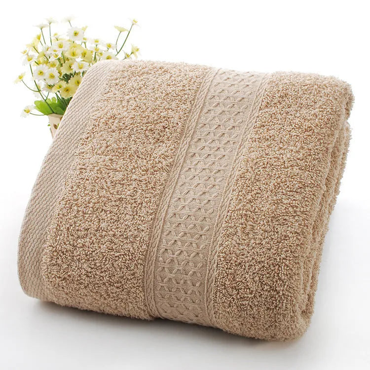 A stack of thickened cotton bath and beach towels in various colours including apple green, dark blue, and light pink.