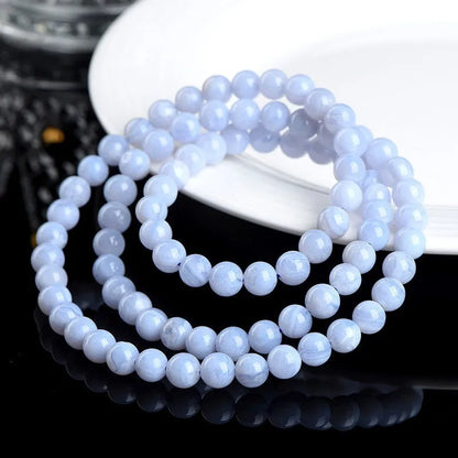 Blue agate bracelet with 6-6.8mm beads in multi-circle pattern and Ruyi elements on a wrist.