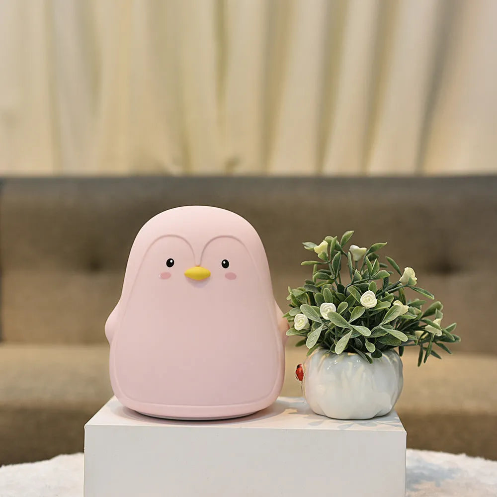 White silicone penguin-shaped USB rechargeable night light on a surface.