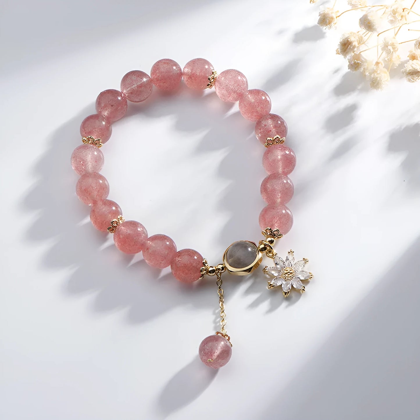 A Mori style crystal bracelet made with natural pink strawberry quartz stones and delicate electroplated floral charms.