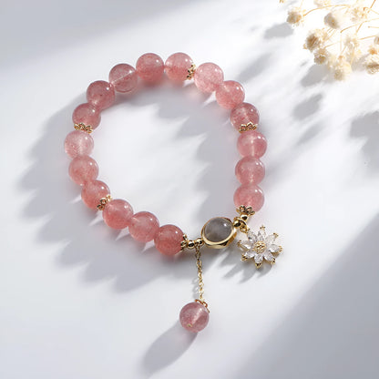 A Mori style crystal bracelet made with natural pink strawberry quartz stones and delicate electroplated floral charms.
