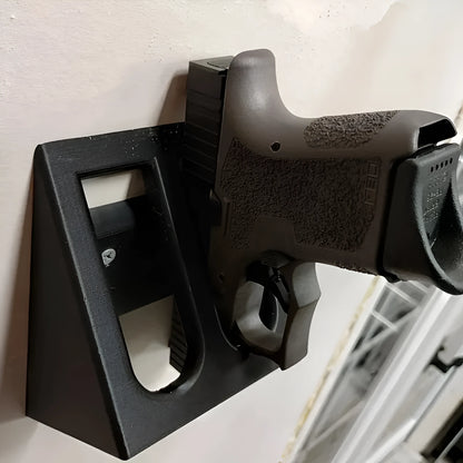 Matte black plastic punk-style pistol display stand on a wooden surface, measuring 10.85cm long.