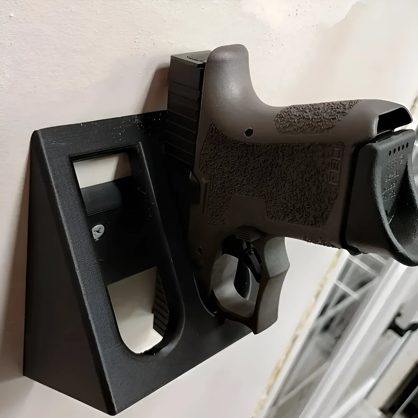 Black pistol-shaped plastic stand for displaying action figures or model collectables on a shelf.