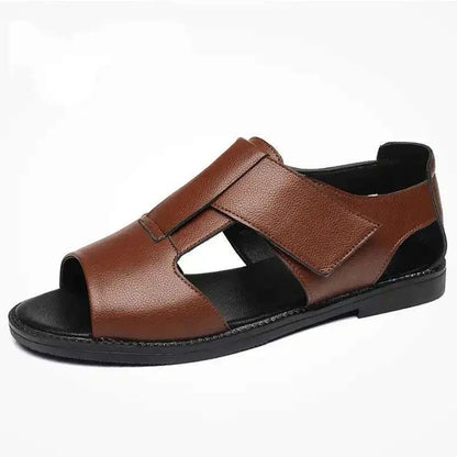 Men's brown leather Roman-style sandals with an open toe and a textured rubber sole on a wooden surface.