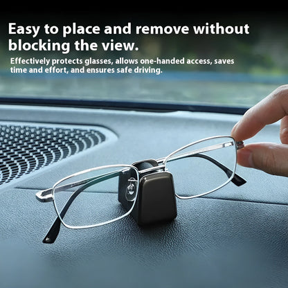 Green zinc alloy and leather glasses clip holder attached to a car dashboard, holding sunglasses.