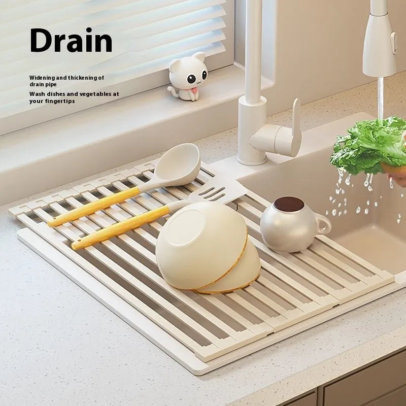 A milky white foldable stainless steel kitchen draining rack collapsed flat beside a kitchen sink.