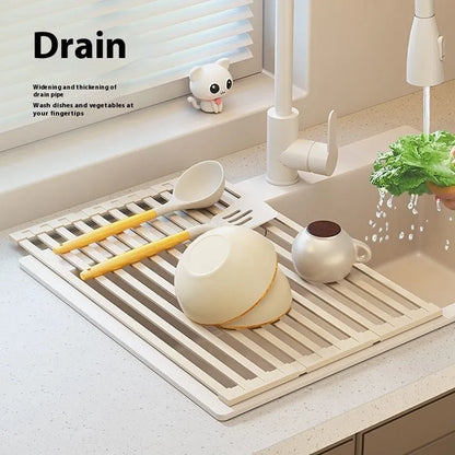 A milky white foldable stainless steel kitchen draining rack collapsed flat beside a kitchen sink.