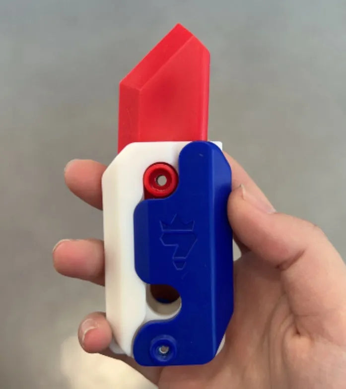 Small orange and green 3D printed plastic carrot knife fidget toy with blade extended.