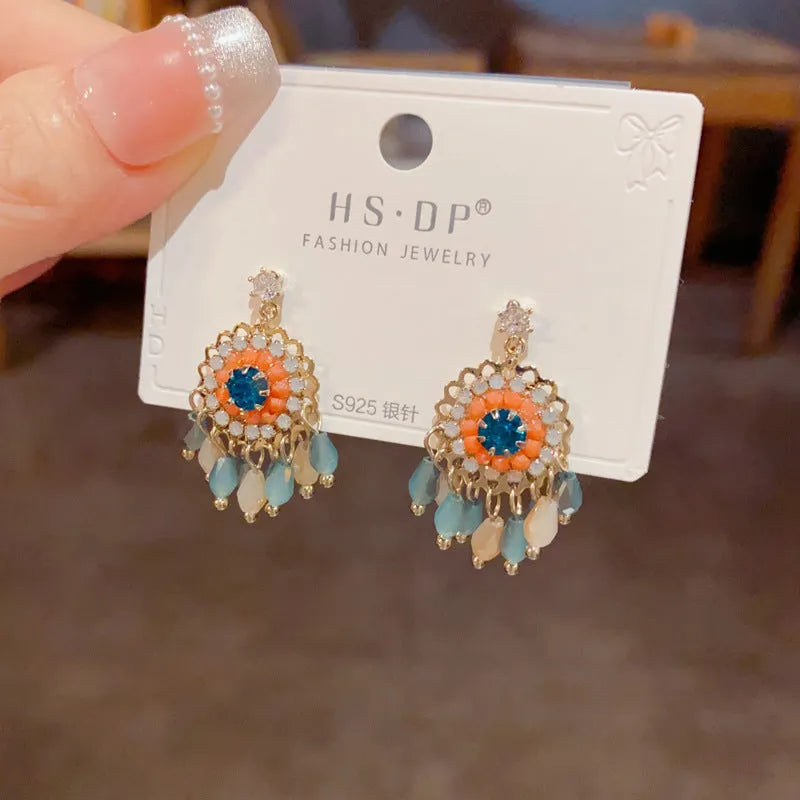 Gold plated geometric earrings with blue diamond-embedded crystals in tassel design