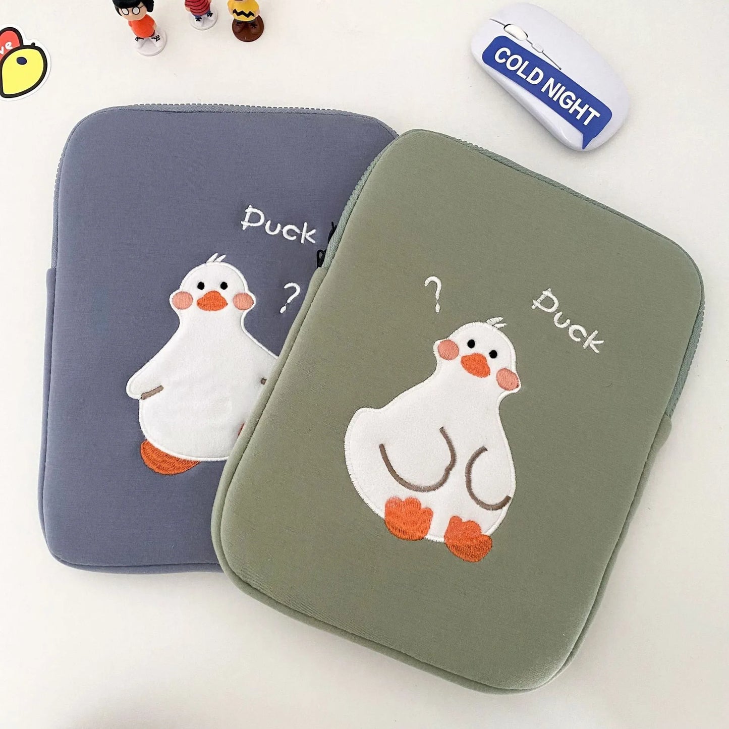 Blue tablet case with embroidered cartoon duck design showing zipper closure and cotton fabric texture