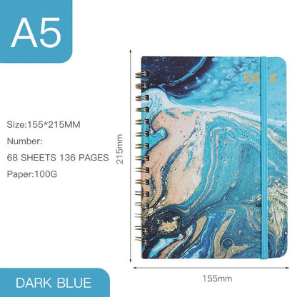 A5 spiral coil notebook open showing annual calendar pages and spiral binding