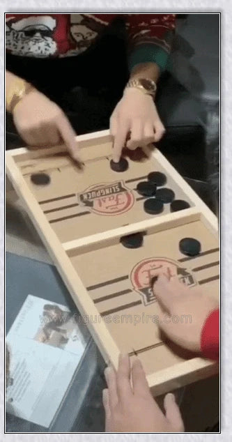 Two players competing in a wooden hockey game with pucks flying across the table
