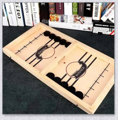 Two players competing in a wooden hockey game with pucks flying across the table