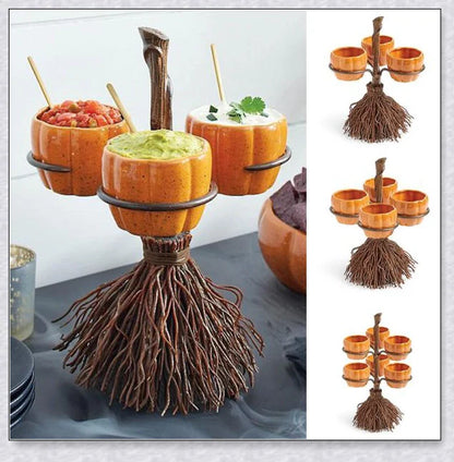 A Halloween-themed snack stand with a broom and three pumpkin-shaped bowls for serving treats and snacks