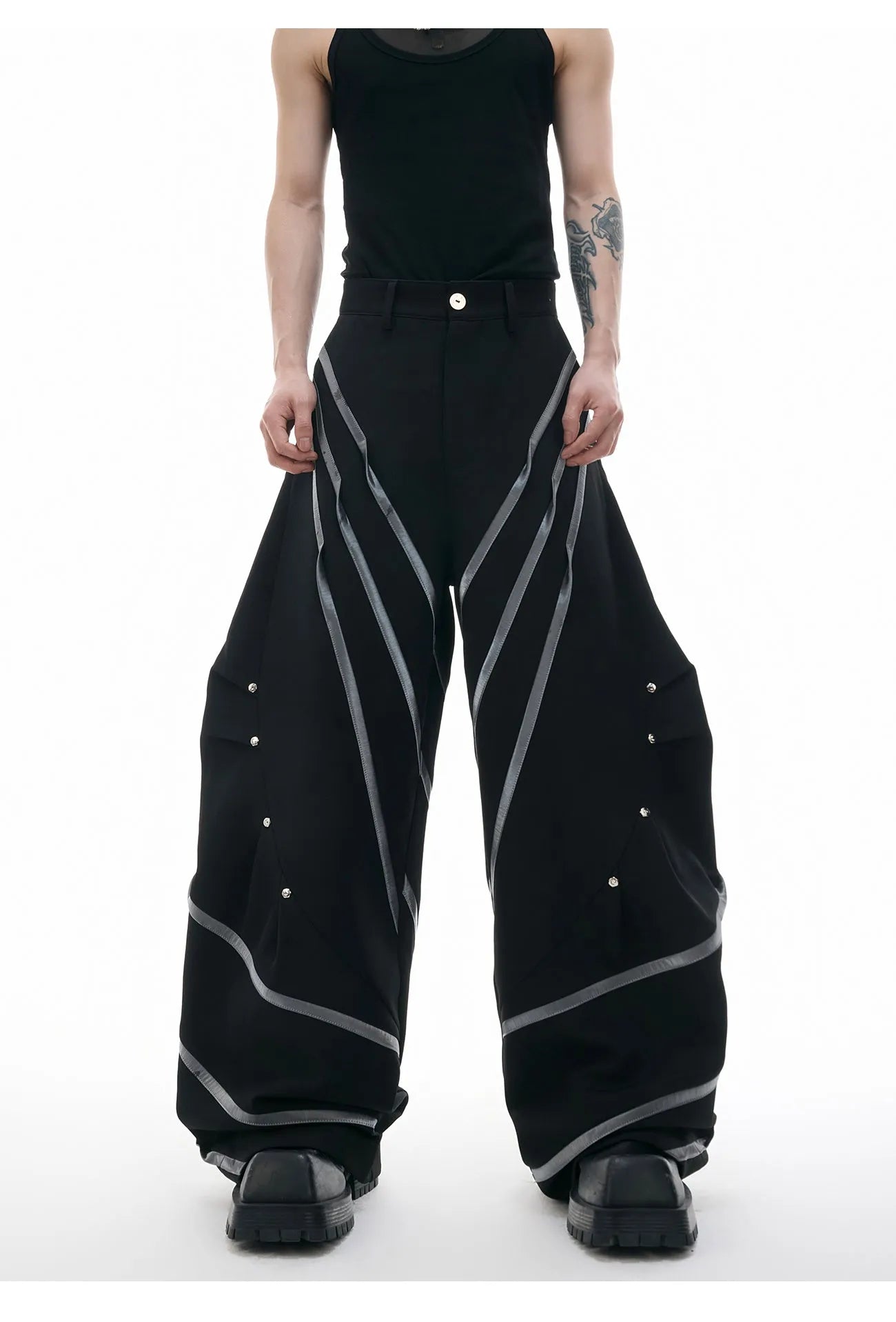 Men's trousers with three-dimensional cutting and metal striped rivet pleats in black or white, showing tailored fit and detail