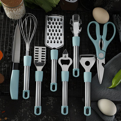 Stainless steel kitchen utensil set with whisk, grater, peeler, scissors and other tools on grey background