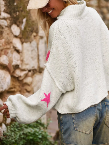 White women's turtleneck pullover with a black star pattern, loose fit, and long sleeves.