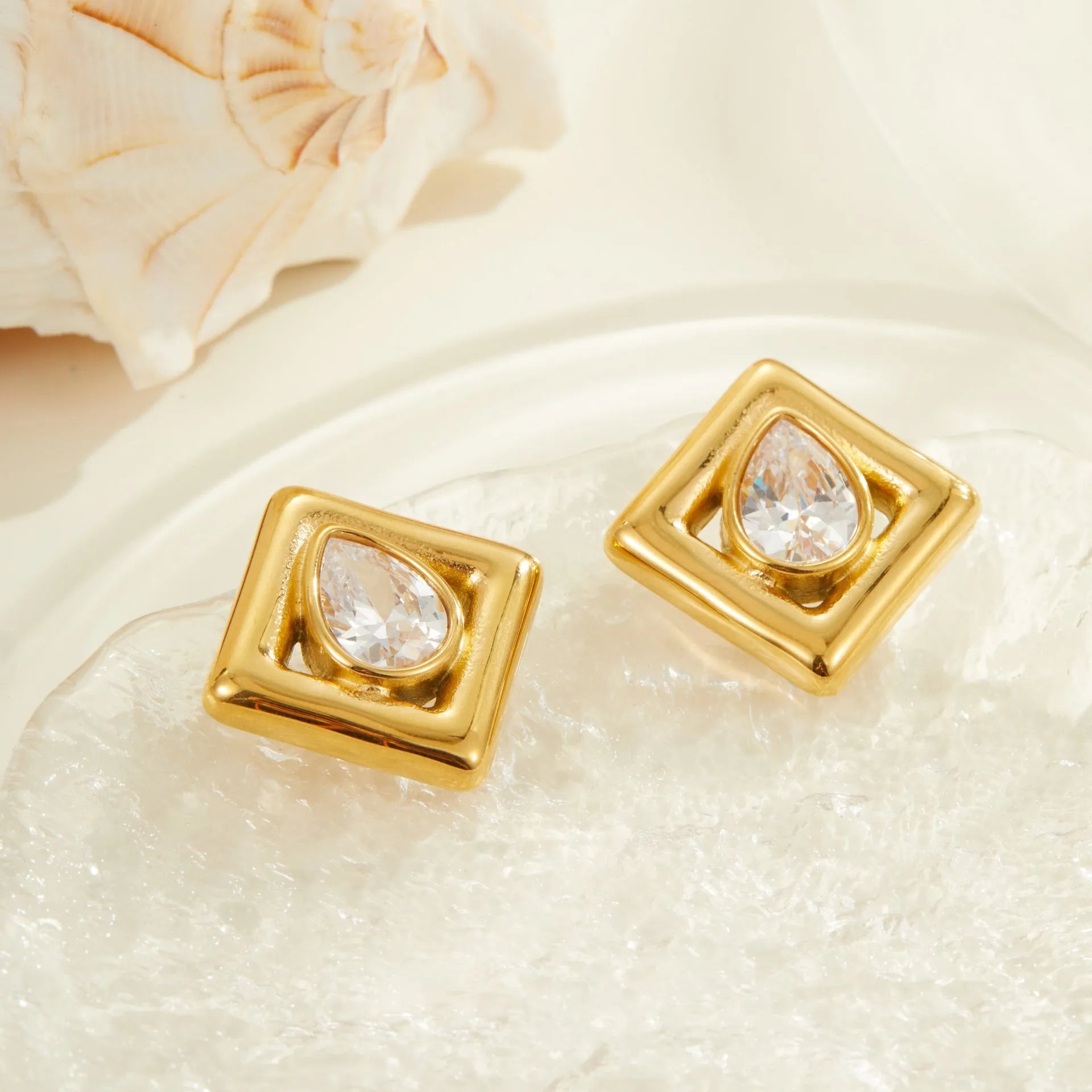 Gold geometric stud earrings for women with inlaid water drop zircon stones on a white background.