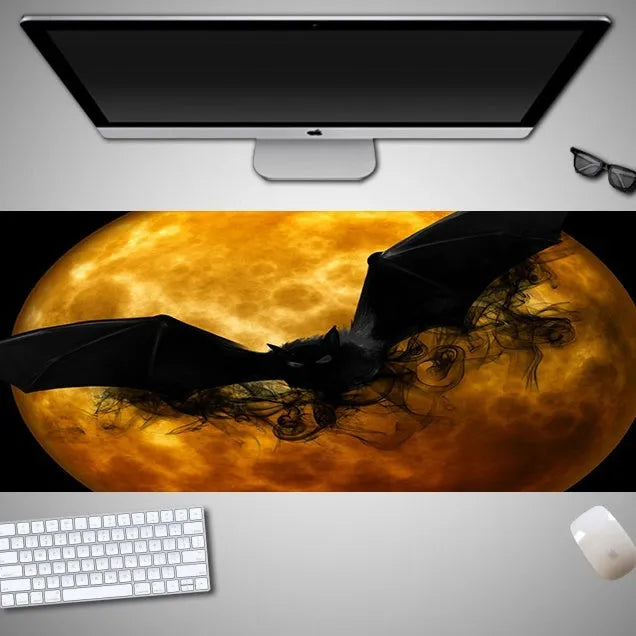 Oversized black Halloween-themed mouse pad with pumpkin design on a wooden desk, showing full 300mm width.