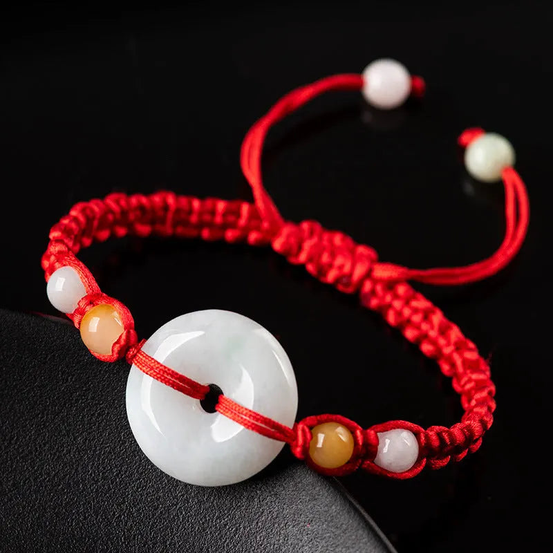 Round emerald green jade pendant on an adjustable red rope bracelet cord.