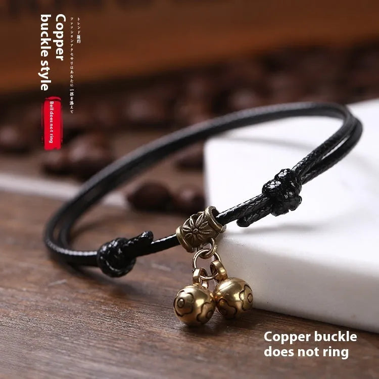A small dog's nylon rope halter collar with a brass bell and buckle on a black background.