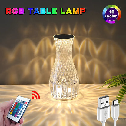 Transparent vase-shaped crystal table lamp with remote control on a wooden bedside table.