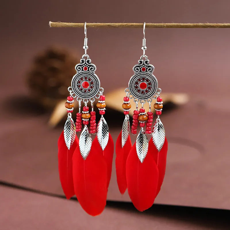 Bohemian feather leaf pattern alloy earrings in round drop shape on a colour selection background.