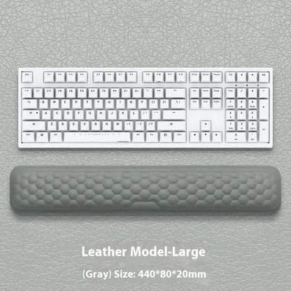 Black and grey memory foam mouse wrist rests with cloth and leather-style covers on a desk.